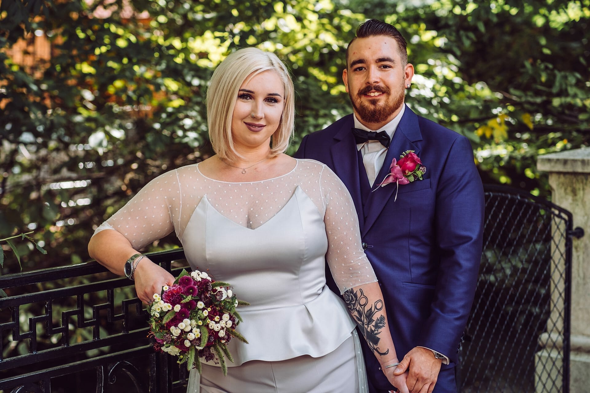 Eine Braut und ein Bräutigam posieren für ein Foto vor einem Zaun.