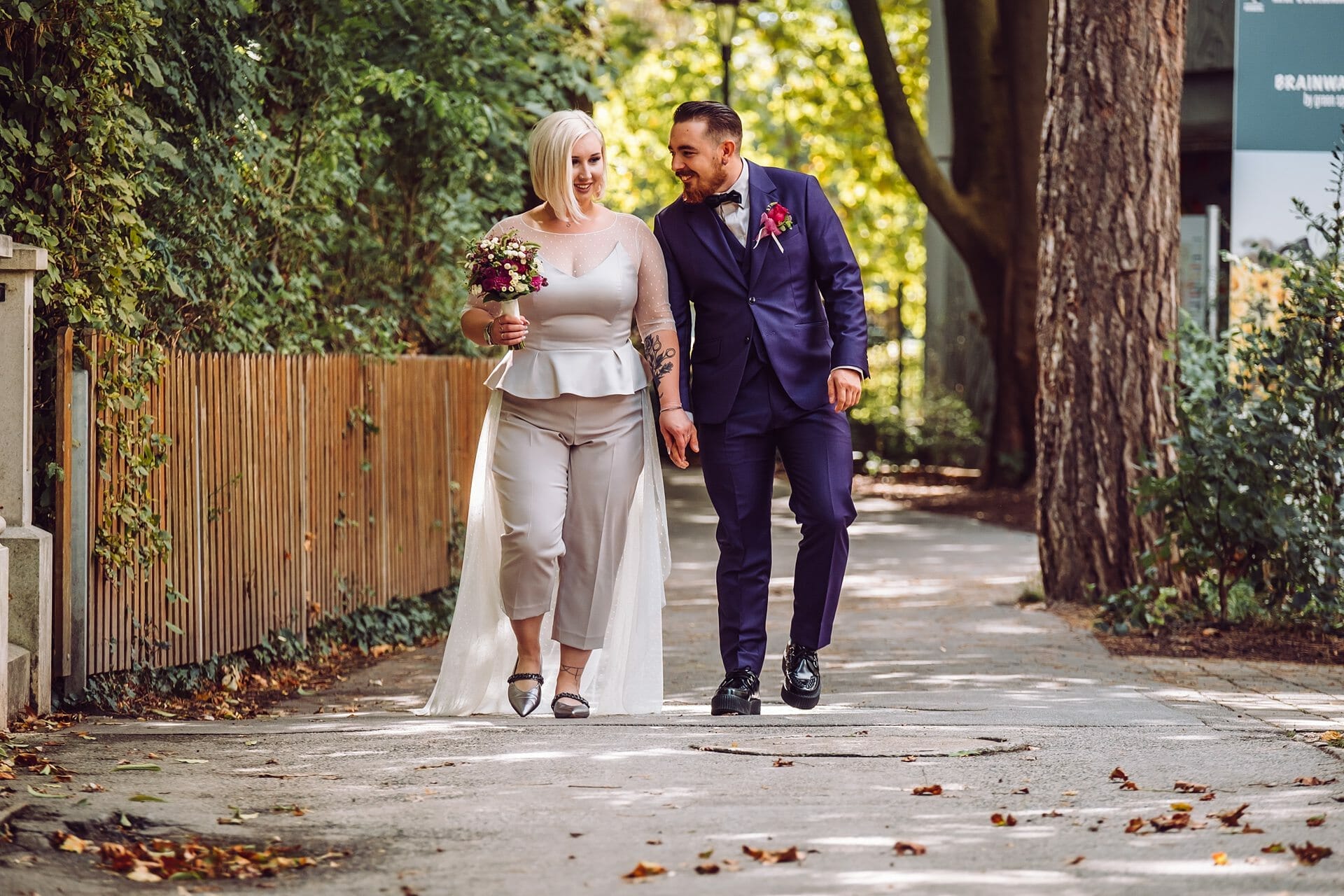 Eine Braut und ein Bräutigam gehen einen Bürgersteig entlang.