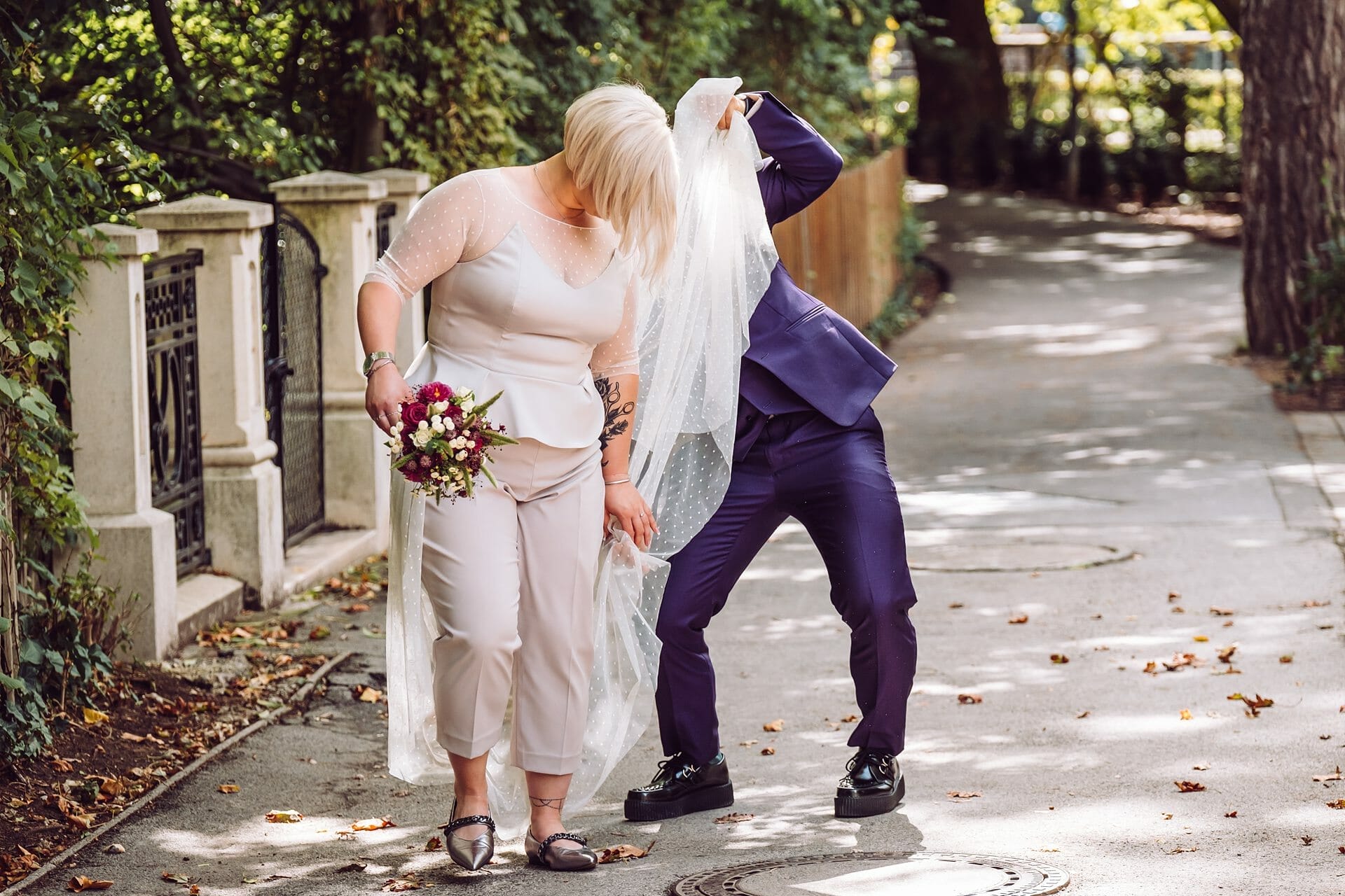 Eine Braut und ein Bräutigam stehen mit einem Schleier auf einem Bürgersteig.