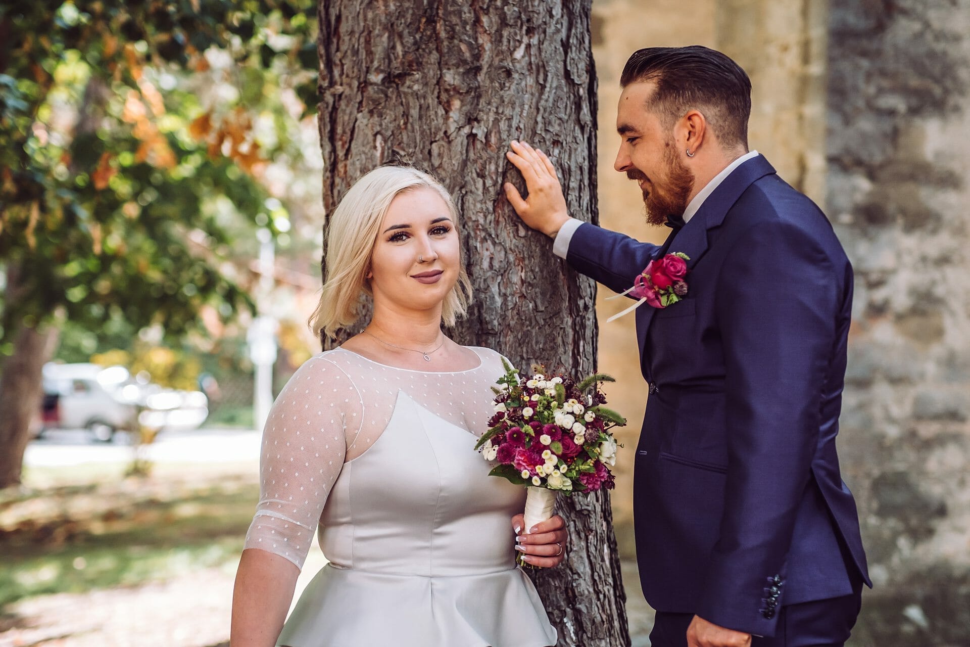 Eine Braut und ein Bräutigam stehen neben einem Baum.