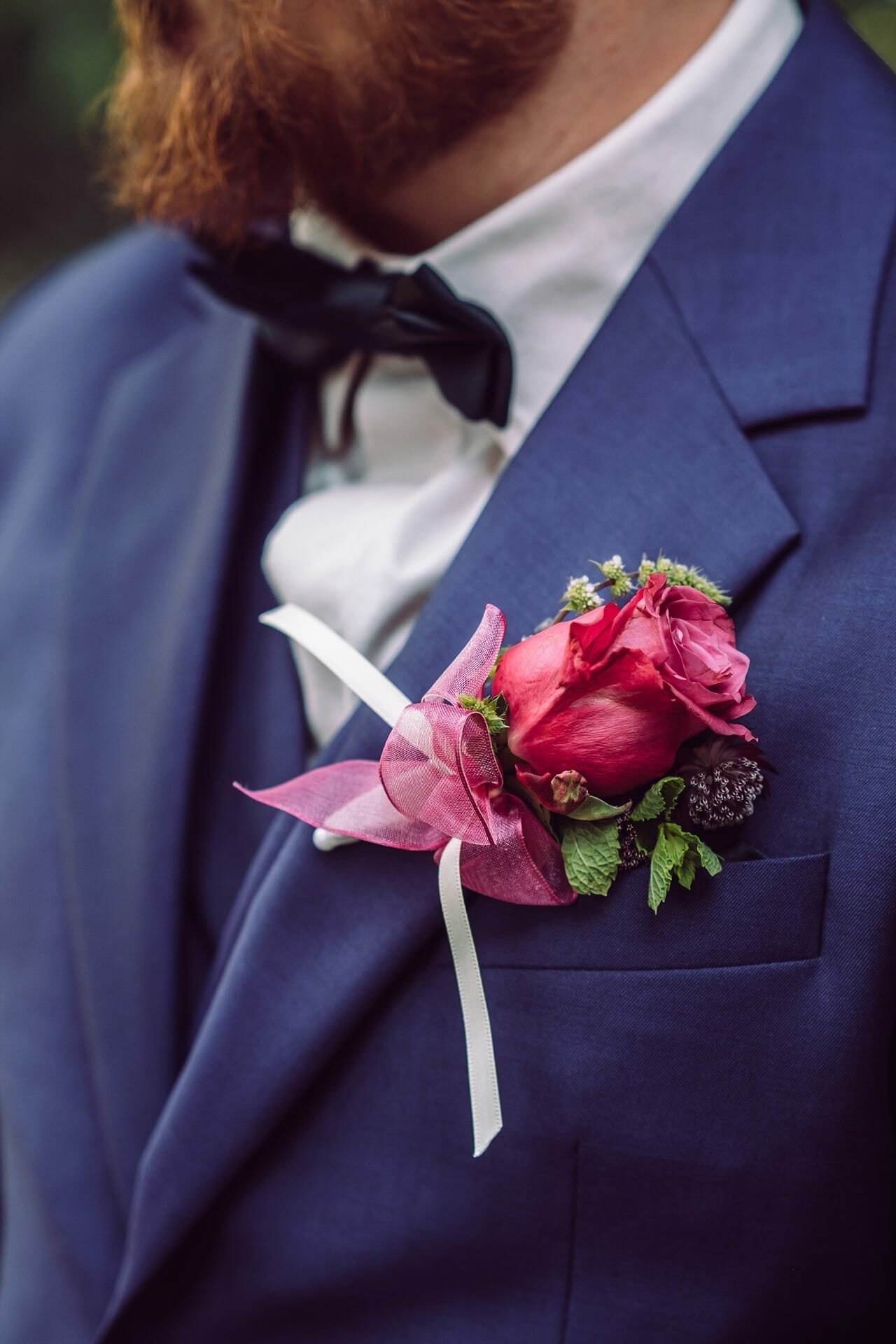 Ein Mann in einem blauen Anzug mit einer rosa Blume am Revers.