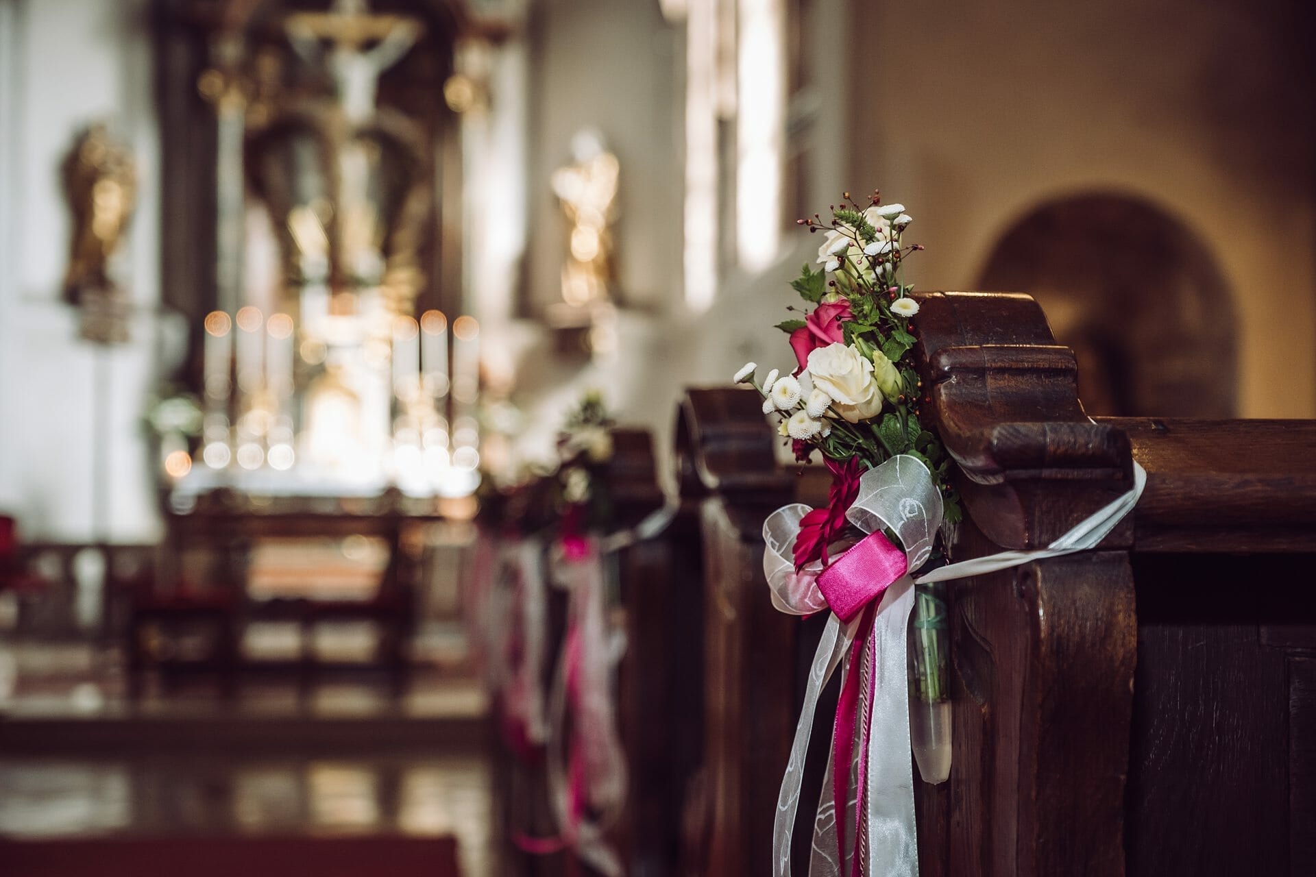 Kirchenbänke mit Blumen und Bändern.