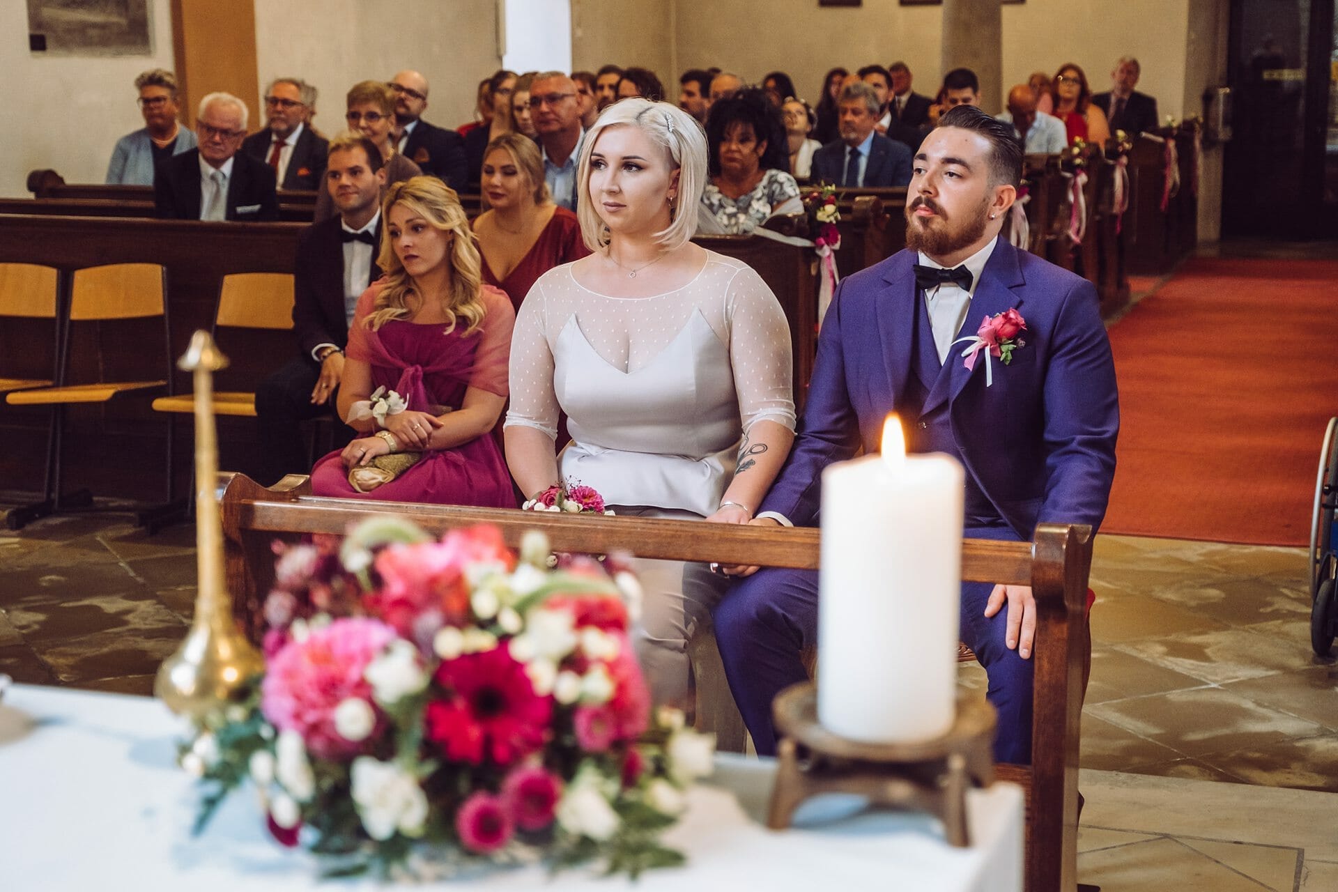 Eine Braut und ein Bräutigam sitzen während ihrer Hochzeitszeremonie in einer Kirche.