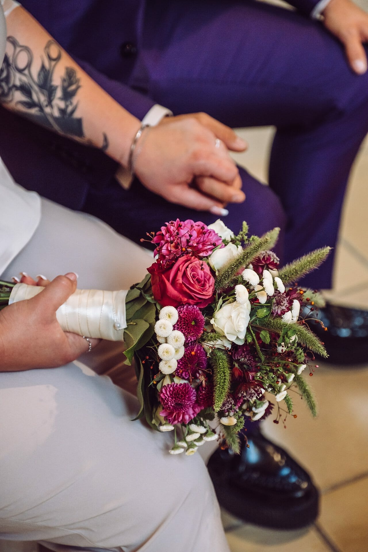 Eine Braut und ein Bräutigam halten einen Blumenstrauß in der Hand.