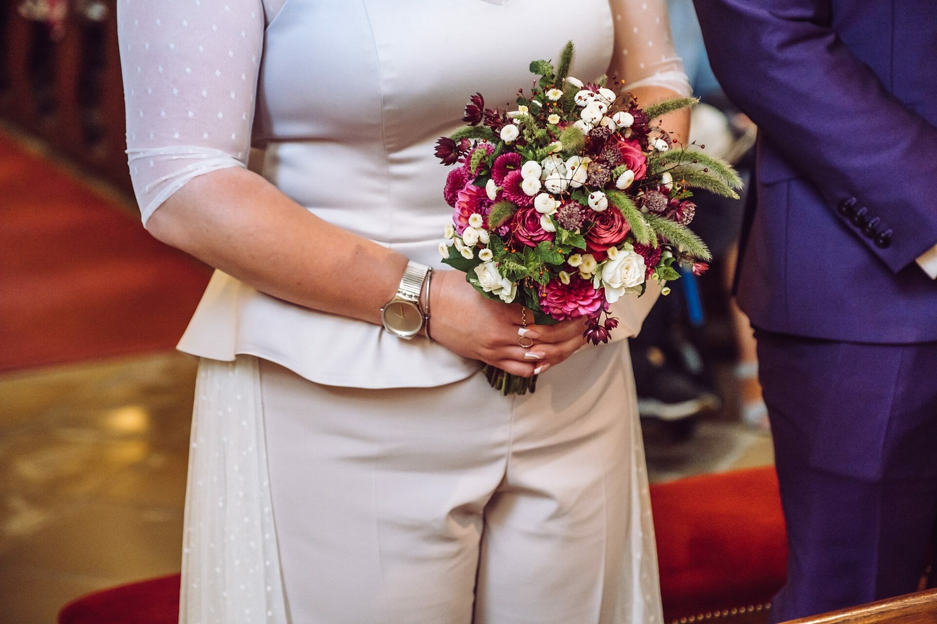 Eine Braut und ein Bräutigam halten einen Blumenstrauß in einer Kirche.