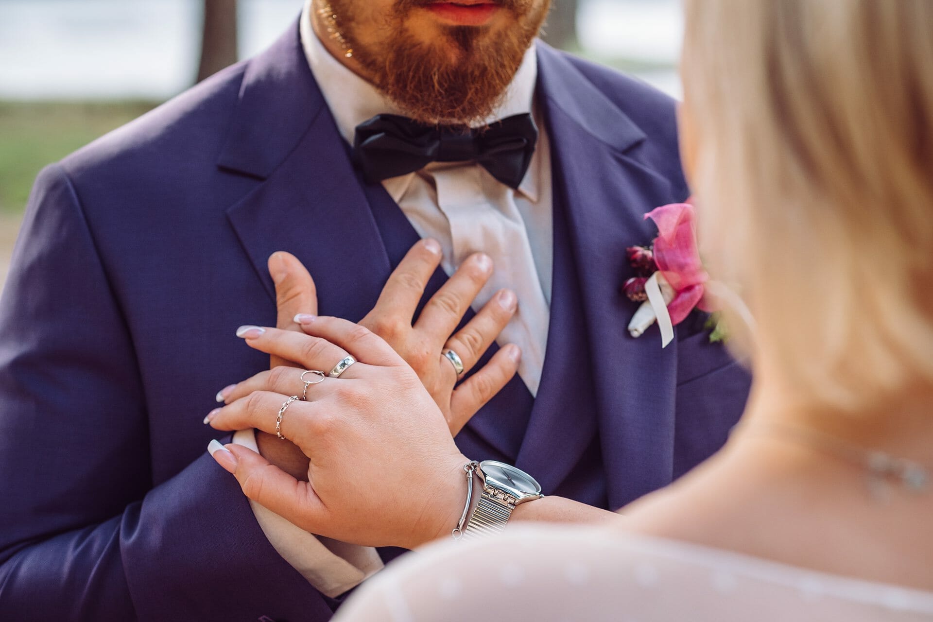 Ein Mann im Anzug steckt einer Braut seinen Ehering an die Hand.